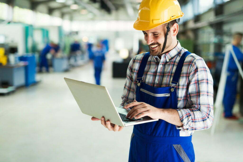 a man wearing a hard hat and looking at a laptop